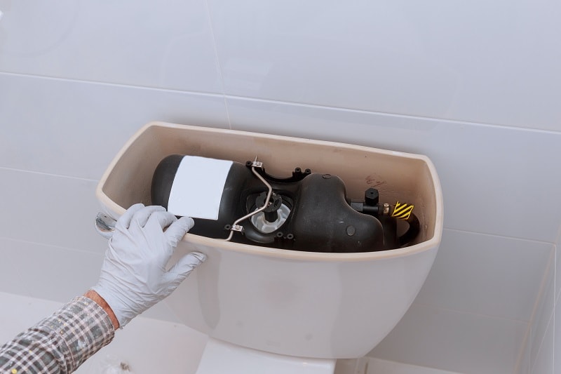 Plumber repairing toilet tank in bathroom plumbing at home changes the toilet